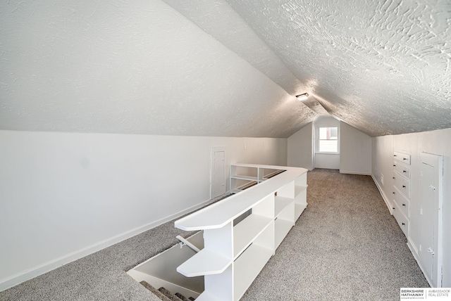 additional living space featuring vaulted ceiling, carpet floors, a textured ceiling, and baseboards