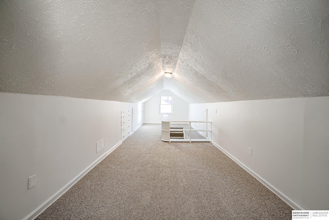 bonus room with lofted ceiling, carpet floors, a textured ceiling, and baseboards