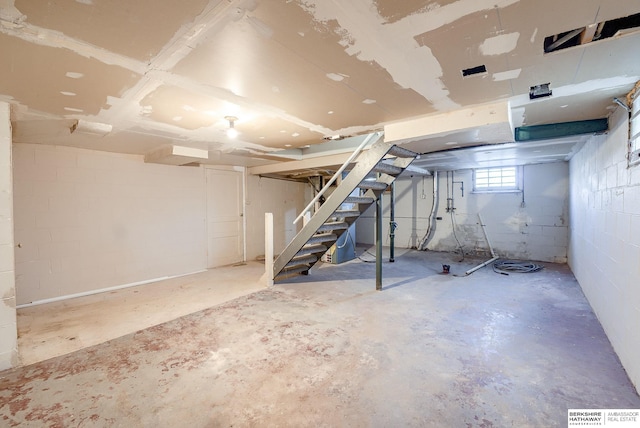 basement with stairs, visible vents, and concrete block wall