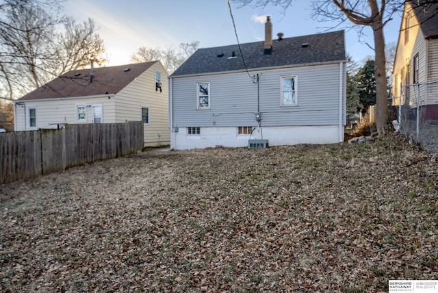 rear view of property with roof with shingles, a chimney, and a fenced backyard