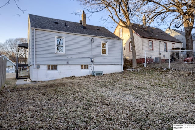 back of house with roof with shingles, fence, a chimney, and central AC unit