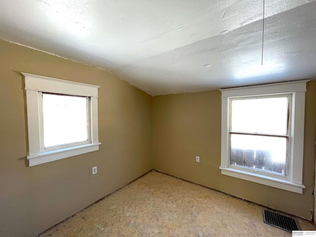 additional living space featuring a wealth of natural light, visible vents, vaulted ceiling, and a textured ceiling