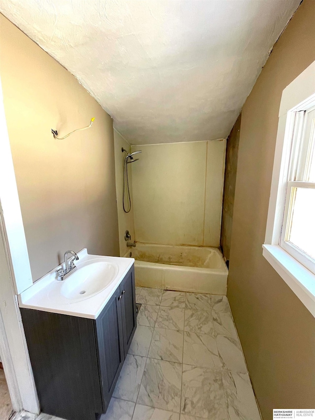 bathroom with marble finish floor, vanity, and washtub / shower combination