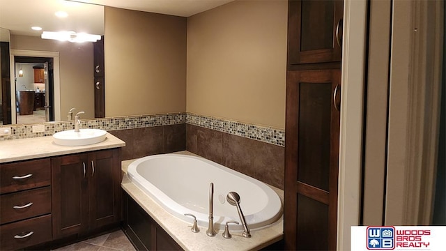 full bath featuring decorative backsplash, a garden tub, vanity, and tile patterned floors