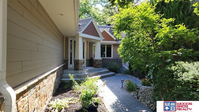 view of home's exterior with stone siding and a shingled roof