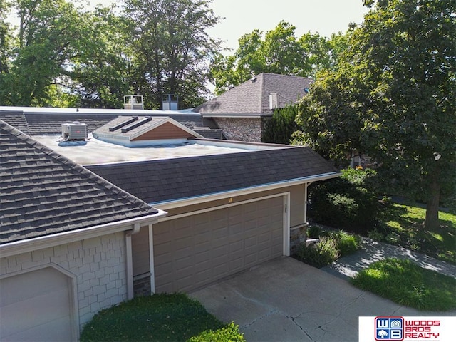 view of property exterior featuring driveway, central AC unit, and roof with shingles