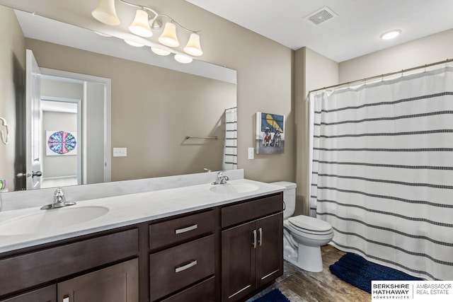 full bathroom with visible vents, a sink, toilet, and double vanity