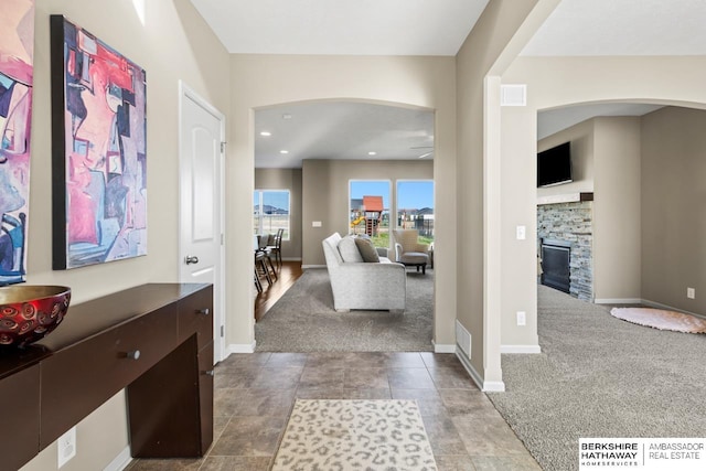 foyer featuring carpet floors, a fireplace, visible vents, and baseboards