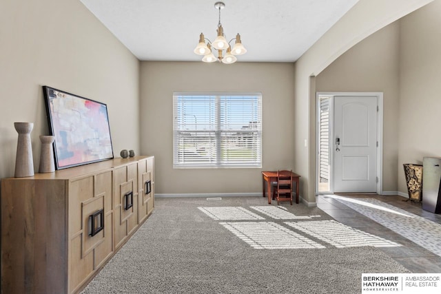 interior space featuring carpet floors, baseboards, and a chandelier