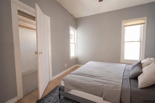 bedroom with light wood-type flooring, multiple windows, and baseboards