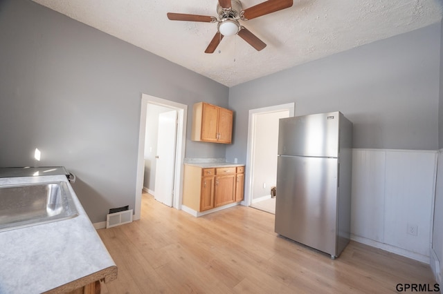 kitchen featuring visible vents, light wood-style flooring, freestanding refrigerator, light countertops, and a sink