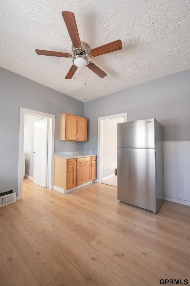 kitchen with light countertops, freestanding refrigerator, visible vents, and light wood-style flooring