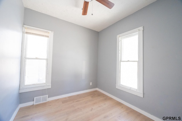 unfurnished room with baseboards, light wood-style flooring, visible vents, and a healthy amount of sunlight