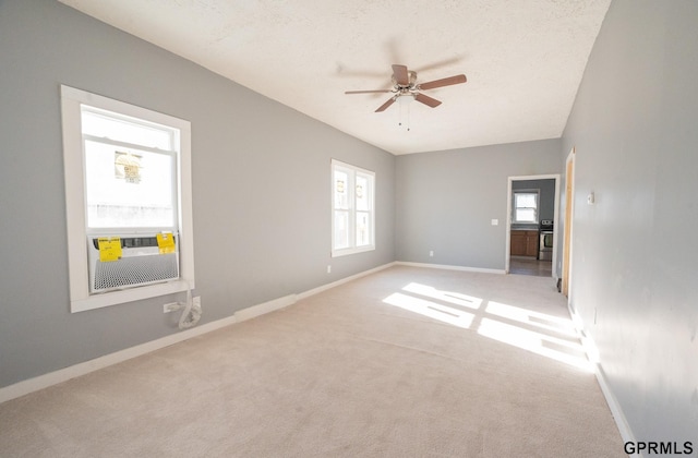 empty room featuring ceiling fan, baseboards, a textured ceiling, and light colored carpet