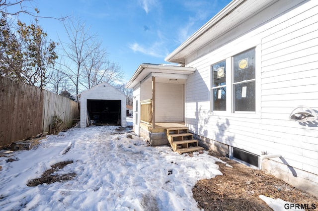 view of snow covered exterior with a garage, an outbuilding, fence, and a storage unit