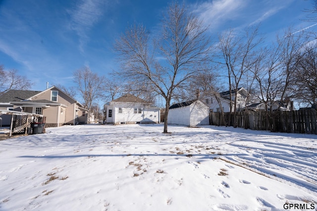 snowy yard with an outbuilding, fence, and a storage unit