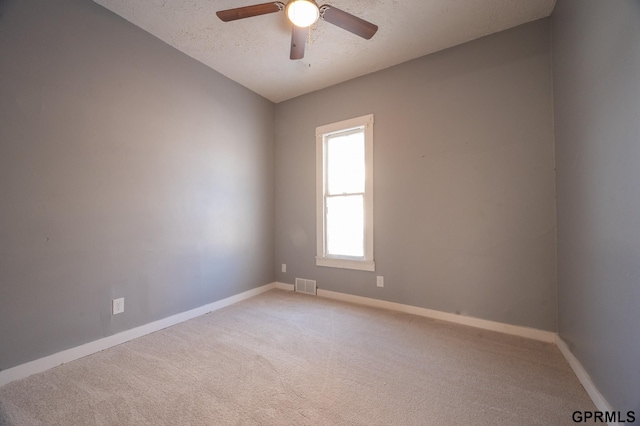 unfurnished room with carpet floors, visible vents, a ceiling fan, a textured ceiling, and baseboards