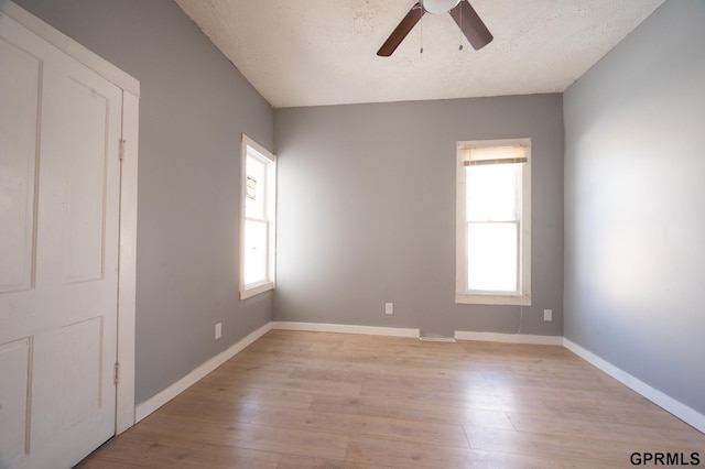 unfurnished room with a textured ceiling, a ceiling fan, light wood-style flooring, and baseboards