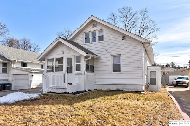 bungalow-style house featuring a garage, a sunroom, an outdoor structure, and a front lawn