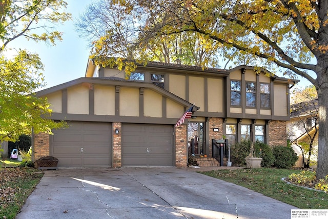 tudor-style house featuring a garage, brick siding, concrete driveway, and stucco siding