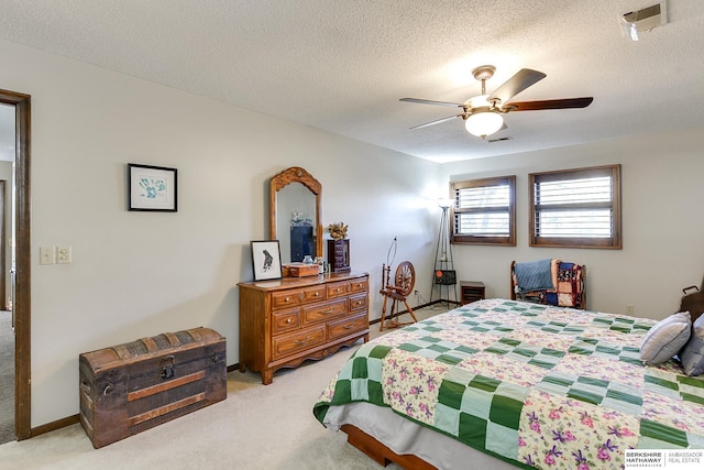 bedroom with a textured ceiling, light carpet, visible vents, a ceiling fan, and baseboards