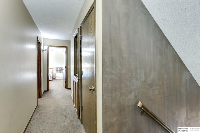 hallway featuring carpet, a textured ceiling, and baseboards