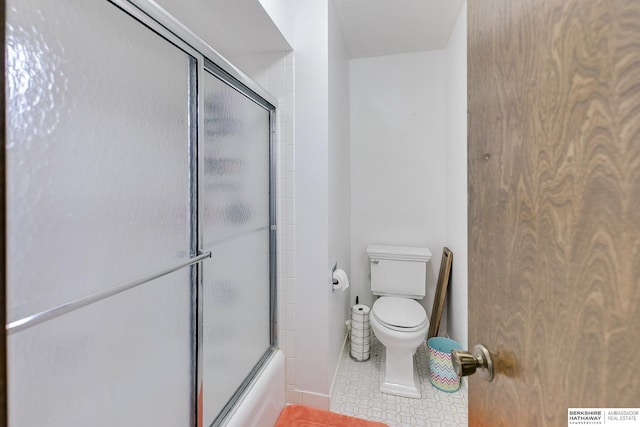 bathroom with shower / bath combination with glass door, toilet, and baseboards