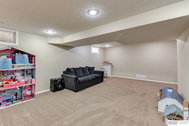 playroom featuring a textured ceiling, carpet flooring, visible vents, and baseboards