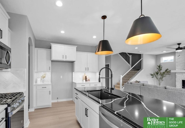 kitchen featuring white cabinets, appliances with stainless steel finishes, pendant lighting, and a sink