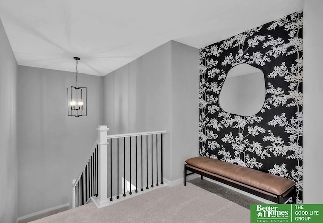 hallway featuring baseboards, carpet floors, an upstairs landing, and an inviting chandelier