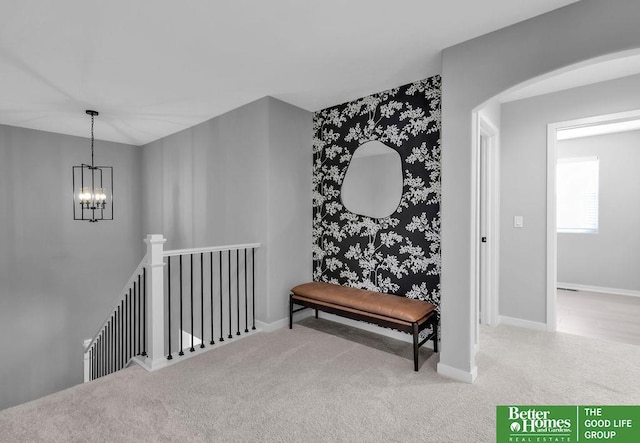 corridor with carpet floors, an upstairs landing, baseboards, an inviting chandelier, and wallpapered walls