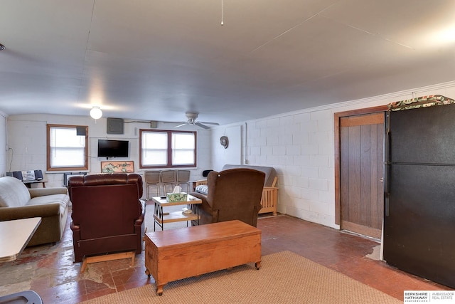 living room with concrete block wall and a ceiling fan