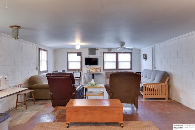 living area with concrete block wall, visible vents, concrete floors, and ceiling fan