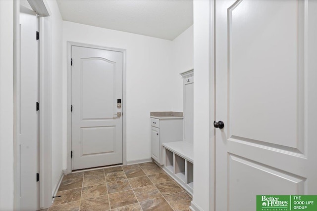 mudroom featuring stone finish flooring and baseboards