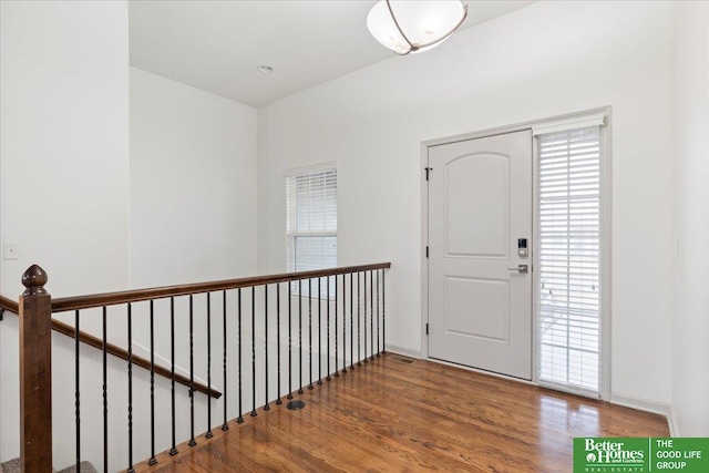 foyer entrance featuring plenty of natural light, visible vents, baseboards, and wood finished floors