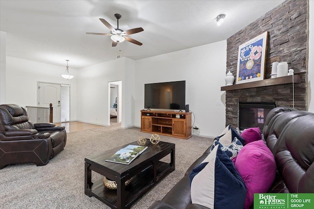 carpeted living room with a stone fireplace, a ceiling fan, and baseboards