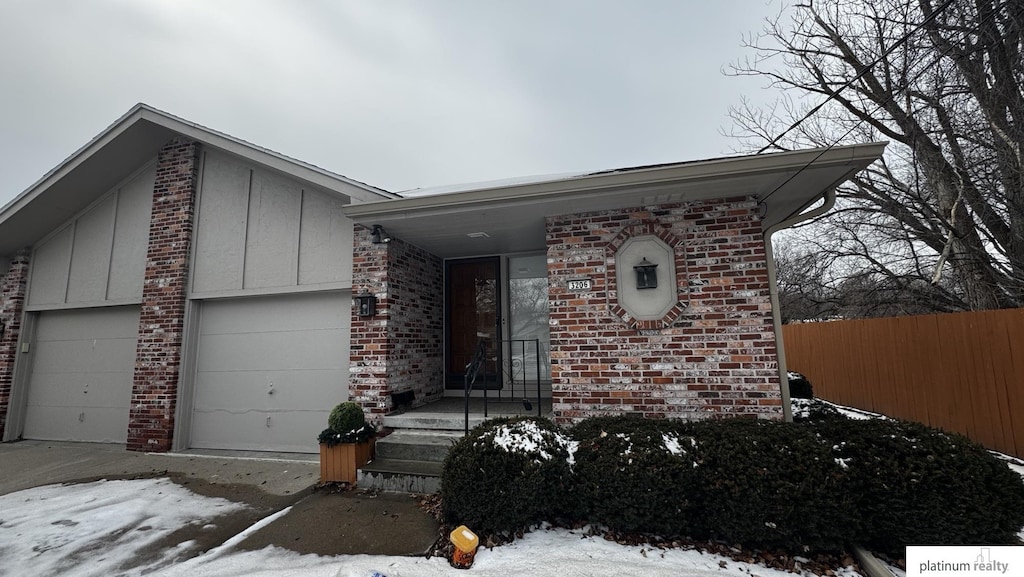 view of front of house with board and batten siding, brick siding, fence, and an attached garage