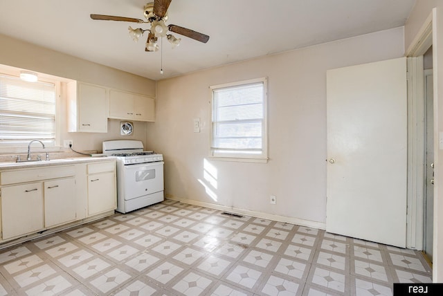 kitchen featuring light floors, white gas range oven, light countertops, and a sink