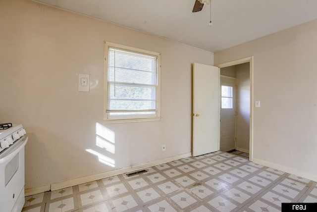 empty room featuring a wealth of natural light, visible vents, ceiling fan, and light floors