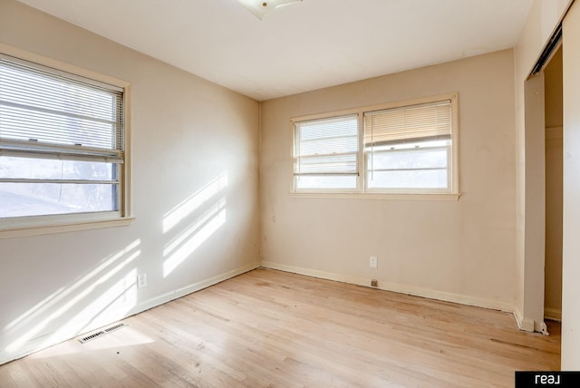 unfurnished room with a healthy amount of sunlight, visible vents, baseboards, and light wood finished floors