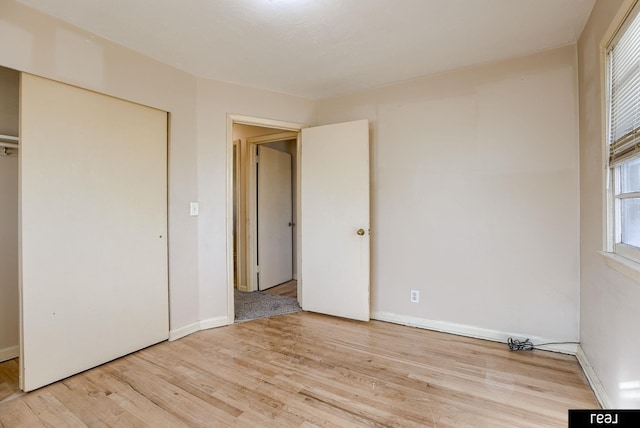 unfurnished bedroom with light wood finished floors, a closet, and baseboards