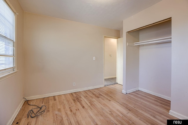 unfurnished bedroom featuring a closet, wood finished floors, and baseboards