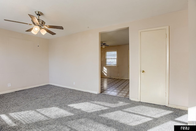 carpeted empty room with a ceiling fan and baseboards