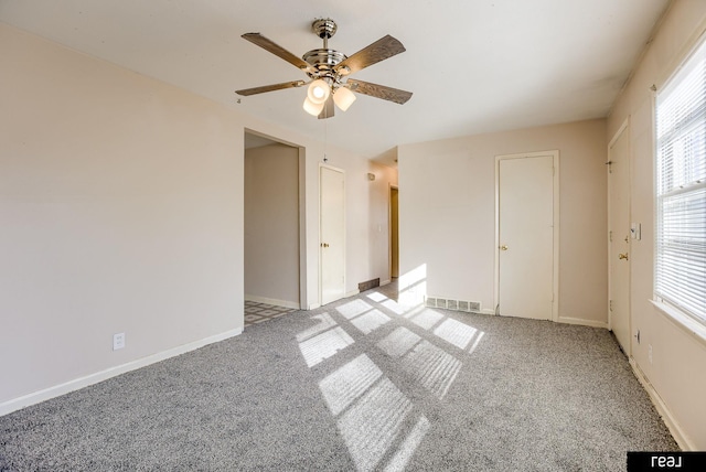 unfurnished bedroom with a ceiling fan, light colored carpet, visible vents, and baseboards