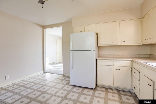 kitchen with visible vents, baseboards, light countertops, freestanding refrigerator, and light floors