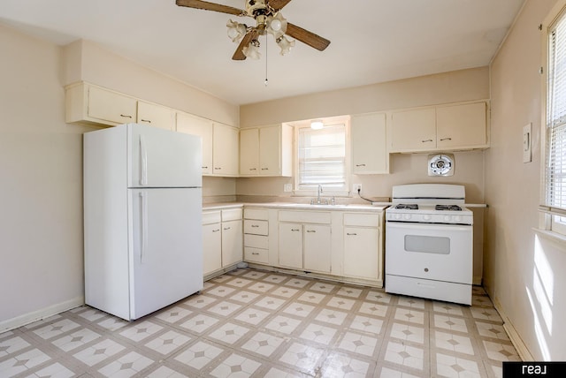 kitchen with white appliances, a ceiling fan, light countertops, light floors, and a sink