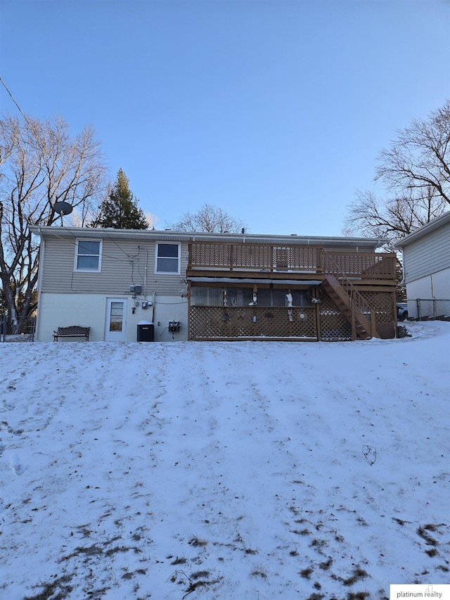 snow covered house featuring stairs, cooling unit, and a wooden deck