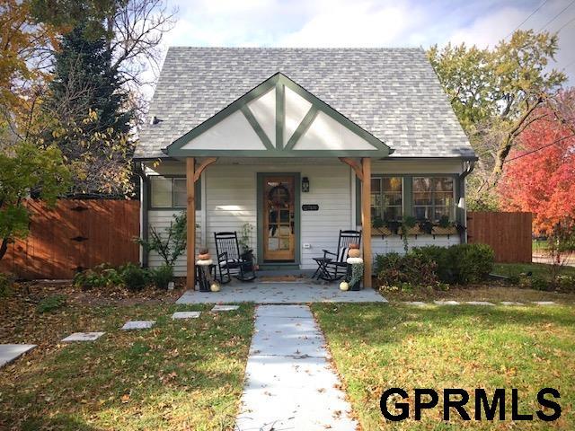 view of front facade featuring covered porch, roof with shingles, fence, and a front lawn