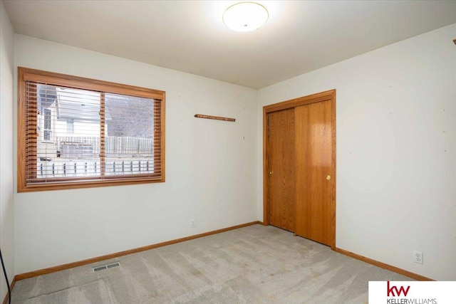 unfurnished bedroom with baseboards, visible vents, a closet, and light carpet