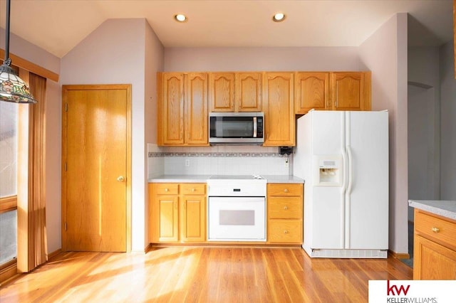 kitchen featuring white appliances, light wood finished floors, light countertops, vaulted ceiling, and backsplash